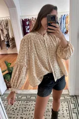 Camisa verde con rayas verticales blancas y bordados de flores. Tiene cuello mao, mangas largas abullonadas con puños elásticos y cierre frontal con botones de nácar.