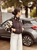 Campera puffer cropped negra con mangas y capucha de polar estampado con diseño geométrico en tonos beige, marrón y negro.