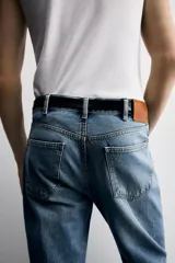 Pantalón de jean celeste, de tiro medio, corte ajustado en la parte superior y acampanado desde la rodilla. Tiene cinco bolsillos, efecto lavado y bajo irregular.