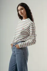 Camiseta de manga larga con cuello redondo, confeccionada en algodón, con un patrón de rayas horizontales blancas y marrones. Presenta un pequeño logo bordado en color rojo en el pecho.