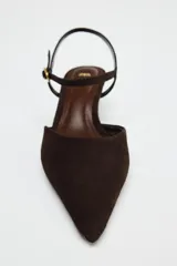 Zapato destalonado de ante color marrón oscuro, con tacón kitten y punta fina. Cierre mediante hebilla en la pulsera al tobillo.
