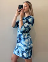 Vestido corto con estampado tie-dye en tonos azules y blancos, de corte recto y mangas cortas.