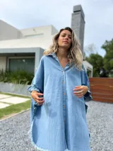 Camisola tipo poncho en jean celeste, con cuello camisero, abotonadura frontal y mangas cortas con volados.