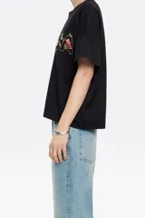 Camiseta blanca de corte boxy con escote redondo, manga corta recta y logo bordado con diseño floral.