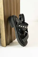 Sandalias negras de charol con tiras cruzadas y plataforma track.