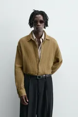 Sobrecamisa color caqui de algodón y lino con efecto arrugado, corte relaxed fit, cuello solapa, manga larga con puños abotonados y cierre frontal con botones.