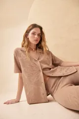 Camisa color beige de tejido calado con cuello camisero, manga corta y cierre frontal con botones.