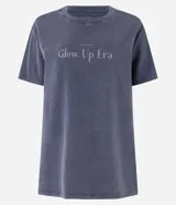 Remera oversized gris con efecto desteñido y estampa frontal con la frase "Glow Up Era".