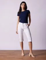 Pantalón capri blanco de algodón elastizado. Pretina con pasadores, botón y cierre. Delantera con bolsillos. Trasera con bolsillos simulados.