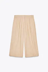Bermudas color beige de tiro alto con trabillas en la cintura, pinzas en el delantero y cierre lateral con cremallera oculta.
