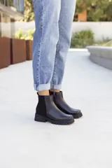Botas de cuero negras con corte estilo chelsea y suela de goma antideslizante.