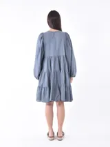 Vestido corto negro con mangas globo abullonadas y cuello redondo. El cuerpo del vestido es ajustado y la falda tiene un corte en capas con volados.