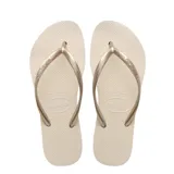 Ojotas Havaianas modelo Slim, color beige con tiras finas metálicas color oro rosado. La suela es texturizada con patrón de arroz.