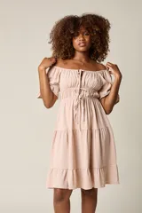 Vestido corto blanco con escote bardot, cintura fruncida y falda escalonada con vuelo.