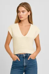 Musculosa color crema de acrílico con punto canalé, corte holgado y escote en V profundo.