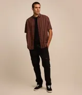 Camisa masculina de corte relajado, confeccionada en cáñamo, algodón y poliéster. Presenta cuello inglés, mangas cortas y rayas verticales texturizadas.