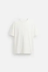 Camiseta regular fit color blanco confeccionada en algodón compacto. Cuello redondo acabado con rib doble y manga corta.
