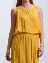 Vestido largo color mostaza de crepe, marca Marissa Olivia. Escote redondo con sobrecapa y detalle de crochet en los hombros. Corte en la cintura con punto smock. Sin mangas.