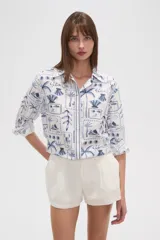 Camisa de lino blanca con estampado de motivos playeros en azul, corte holgado, cuello camisero y cierre frontal con botones.