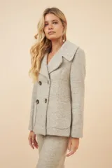 Chaquetón color crema con doble solapa, abrochadura doble, bolsillos delanteros y forro al tono.