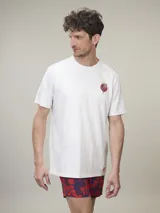 Remera de manga corta color gris jaspeado, confeccionada en algodón, con cuello redondo y estampado pequeño de corazón con flores en el pecho. Corte clásico.