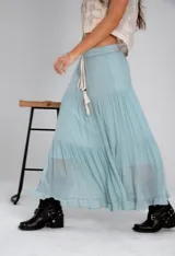 Pollera larga de color rosa pálido, con corte en capas y cintura elastizada. Incluye lazo fino del mismo material.