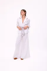 Pantalón de tiro alto, corte ancho y largo, color beige claro con finas rayas verticales en tono oscuro. Presenta cierre frontal con botón y bolsillos tipo jean.