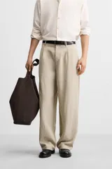 Pantalón color beige de corte ancho, con pliegues frontales, bolsillos laterales y traseros de doble vivo.
