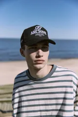 Gorra negra de 5 paneles con cierre snapback ajustable y bordado frontal con logo.