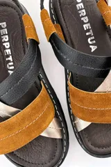 Sandalias de cuero con tiras cruzadas color marrón, negro y dorado, con hebilla de ajuste y suela de goma negra.