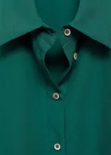 Camisa verde esmeralda de corte recto, con cuello camisero, mangas cortas y cierre frontal con botones.