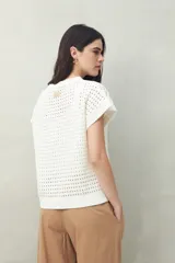 Chaleco tejido color crudo con diseño calado, cuello redondo y mangas cortas. Corte holgado.