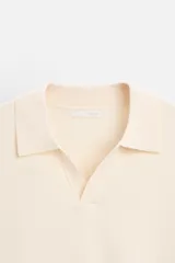 Polo color crema de punto, corte regular fit, cuello solapa con abertura frontal y manga corta.