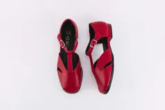 Zapatos bajos rojos de cuero, con puntera redondeada y tira central con hebilla. Presentan aberturas laterales.