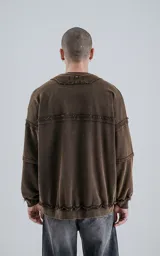 Buzo marrón de cuello redondo con costuras expuestas, calce oversize crop y proceso de desgaste.