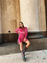 Vestido corto fucsia de terciopelo, con mangas largas abullonadas y falda drapeada.