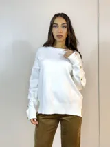 Sweater blanco de punto con cuello redondo y mangas largas con detalle de botones dorados en los puños.