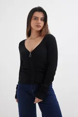 Sweater negro de tejido de punto acanalado, con escote en V y cierre frontal con cremallera metálica.