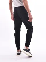 Pantalón jogger de denim azul con cintura elástica ajustable con cordón blanco, bolsillos laterales y puños elásticos.