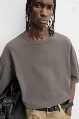 Camiseta color gris verdoso de punto tejido en hilatura de algodón, con cuello redondo, manga corta, efecto lavado y acabados irregulares.