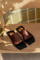Sandalias planas color marrón con capellada tejida y base cuadrada color negro.