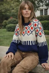 Sweater de lana merino color crema con cuello alto y diseño con motivos geométricos en amarillo, naranja, violeta y negro.