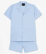 Pijama americano celeste, compuesto por camisa de manga corta con cuello solapa y botones frontales, y bermuda con cintura elástica.