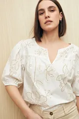 Blusa blanca con calados y bordados florales, escote en pico y mangas abullonadas con puño elastizado.