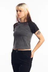 Remera corta gris con mangas ranglan negras y logo ovalado en el pecho.