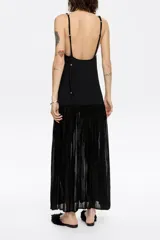 Vestido largo negro de punto con corte ajustado en la cadera y falda con vuelo, escote recto y tirantes dobles con aros metálicos y nudos.