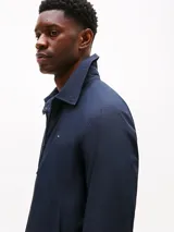 Campera azul marino de poliéster con cuello inglés, cierre frontal de cremallera, dos bolsillos laterales con cremallera y puños con cierre a presión. Presenta un logo de Tommy Hilfiger bordado en el pecho.