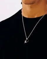 Collar plateado con cadena de eslabones finos y dije con piedra negra y estrella.