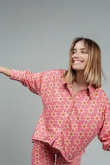 Camisa de manga larga color rosa con estampado de flores naranjas y blancas, de corte holgado y cuello camisero.