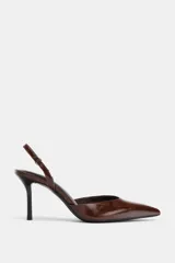 Zapato de tacón alto, color marrón oscuro brillante, con punta fina y diseño destalonado con tira ajustable en el talón.